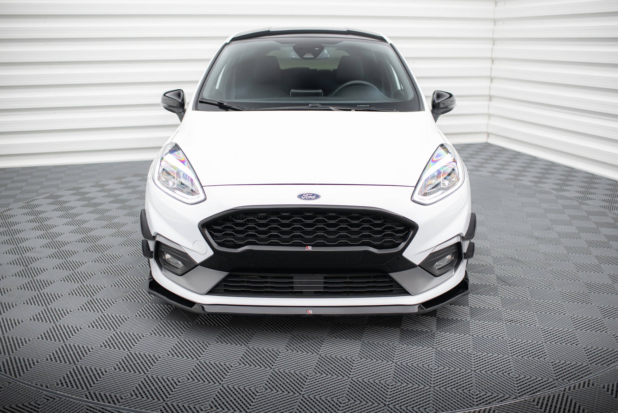 Frontleppe på Ford Fiesta MK8 ST med svarte detaljer, sett forfra i lyst rom med gråmønstret gulv.