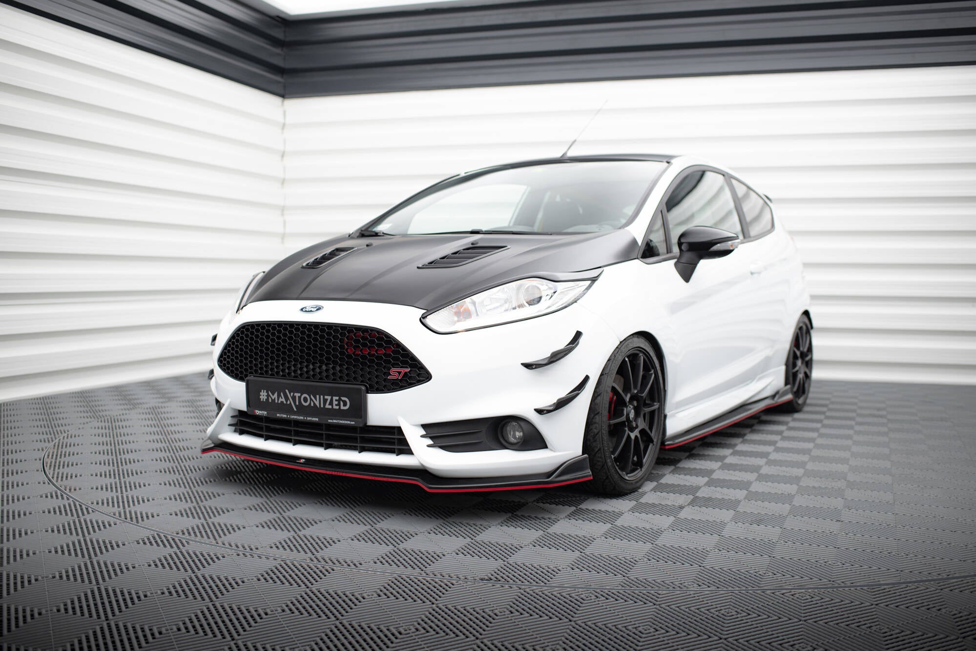 Front splitter på Ford Fiesta St MK7 Facelift V.5 med røde detaljer og svarte felger, sett fra front hjørne.