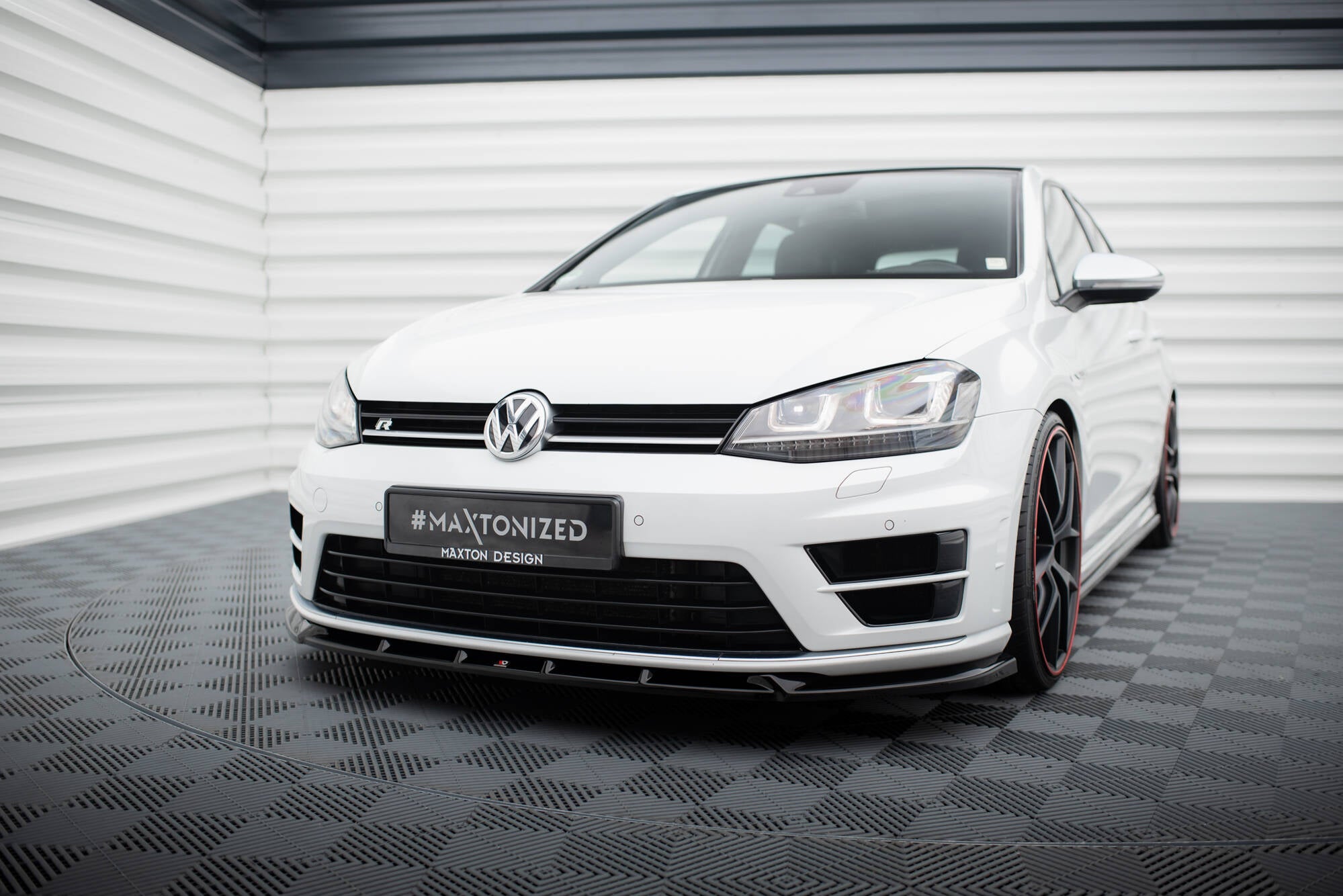 Frontspoiler VW Golf R / R-Line MK7 med svarte detaljer og sporty frontsplitter, sett forfra i lyst rom.