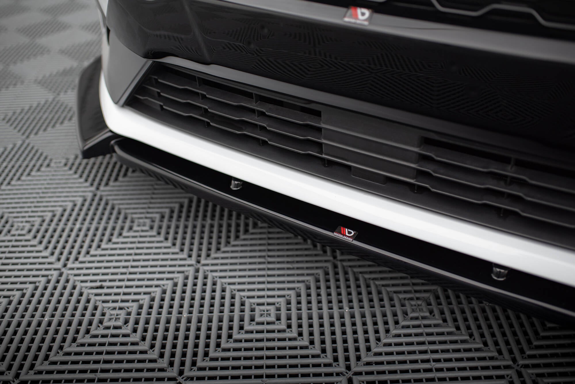 Spoiler til Ford Fiesta MK8 St-Line V.7 i sort og hvit plast, sett skrått montert på bil med røde detaljer.