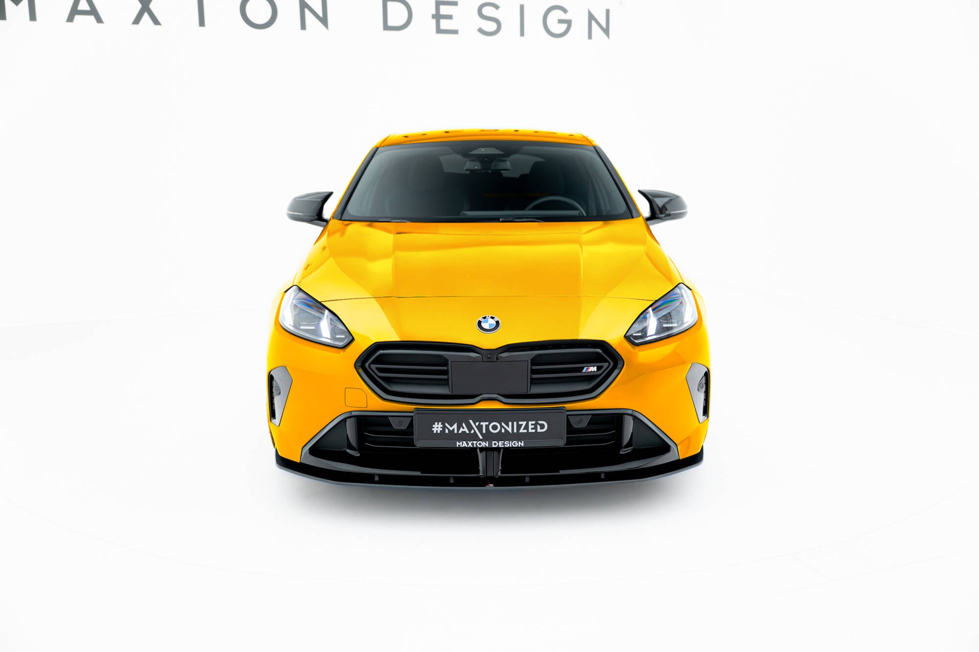 Frontleppe på BMW F70 1 M-Pakke, gul sportsbil forfra med svart grill og aerodynamiske detaljer.