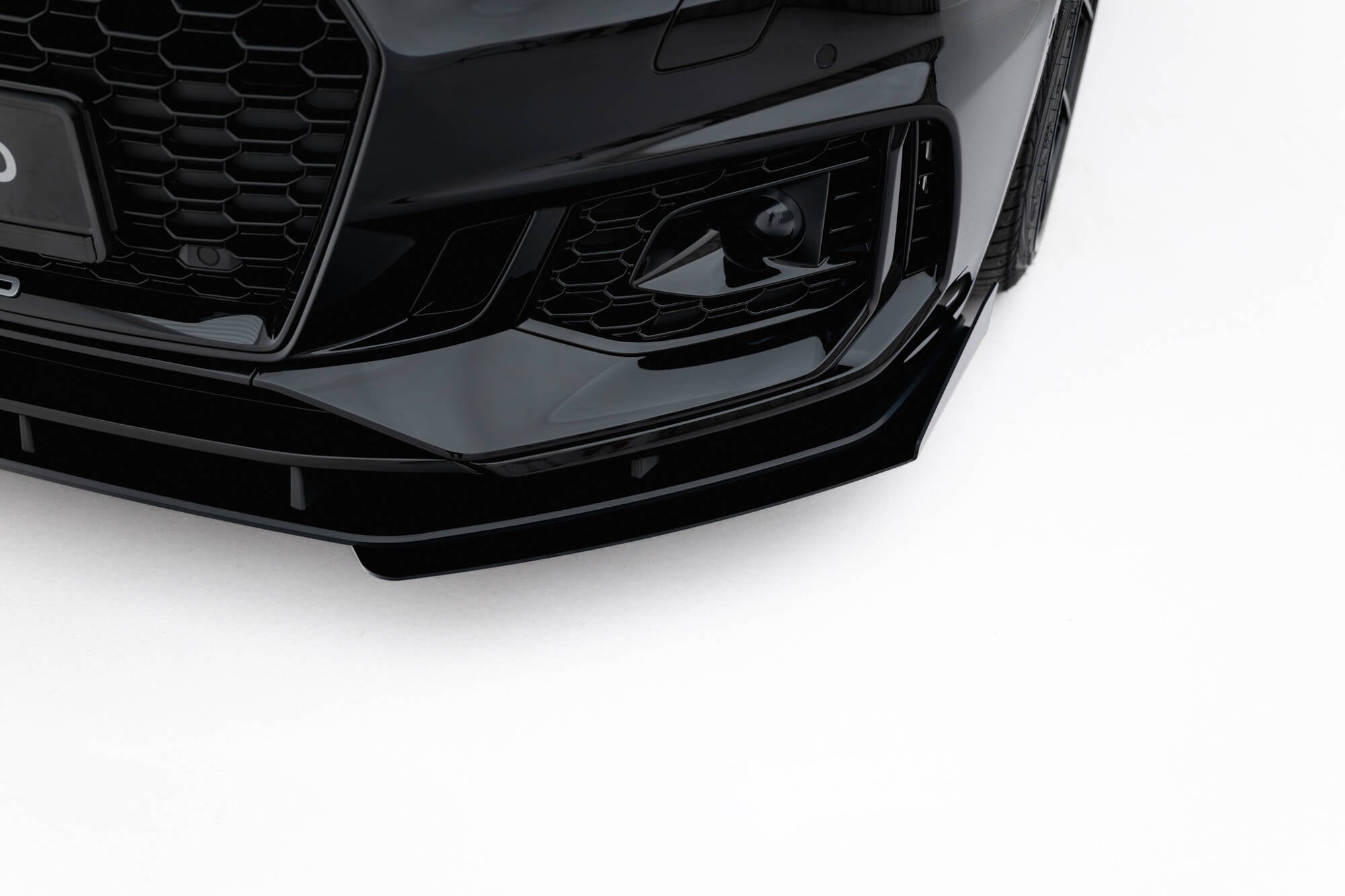 Spoiler til Audi RS5 Coupe Sportback F5 V2 i blank sort plast sett skrått forfra mot hvit bakgrunn.
