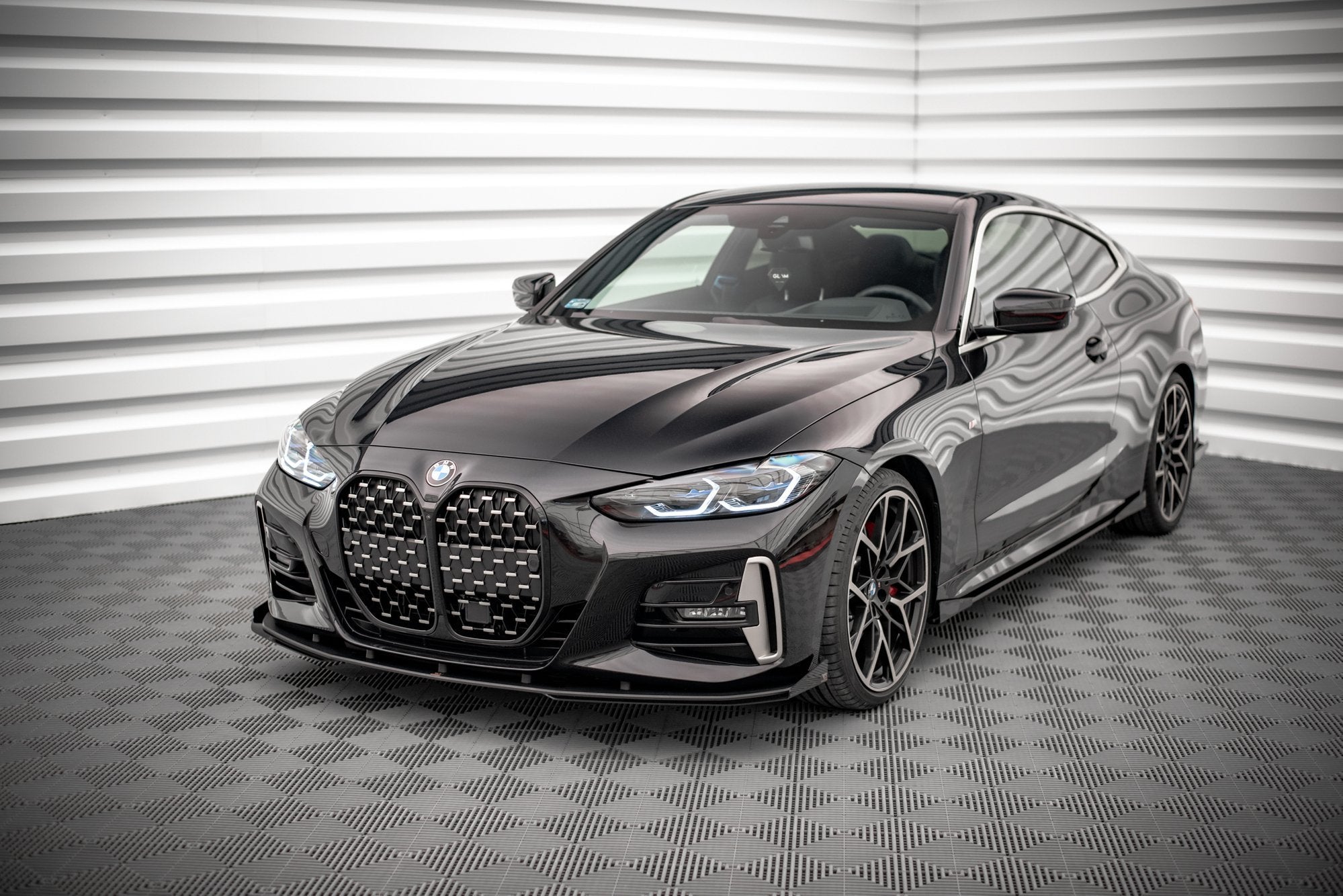 Frontspoiler BMW 4 M-Pakke M440I G22 Facelift sort coupé sett skrått forfra med svarte felger.