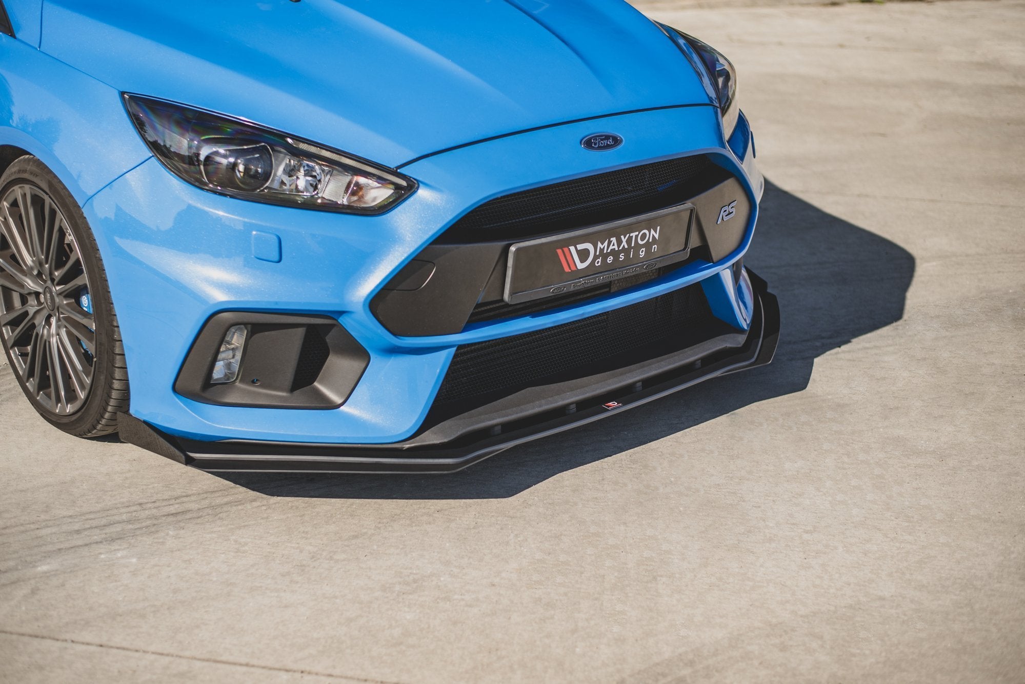 Spoiler til Ford Focus RS MK3 10mm V2, svart frontsplitter på blå bil med Maxton Design-logo.