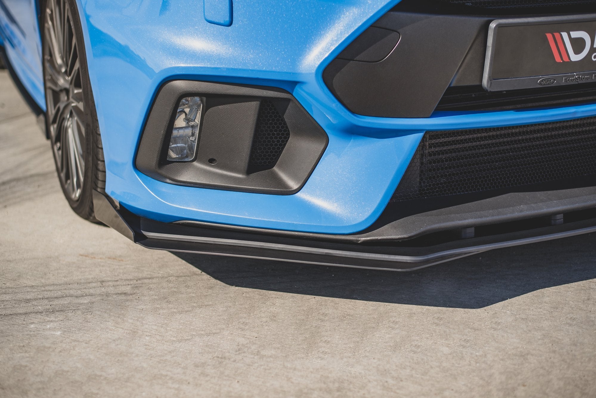Front splitter på Ford Focus RS MK3 10mm V2, nærbilde med svarte detaljer og luftinntak utendørs.
