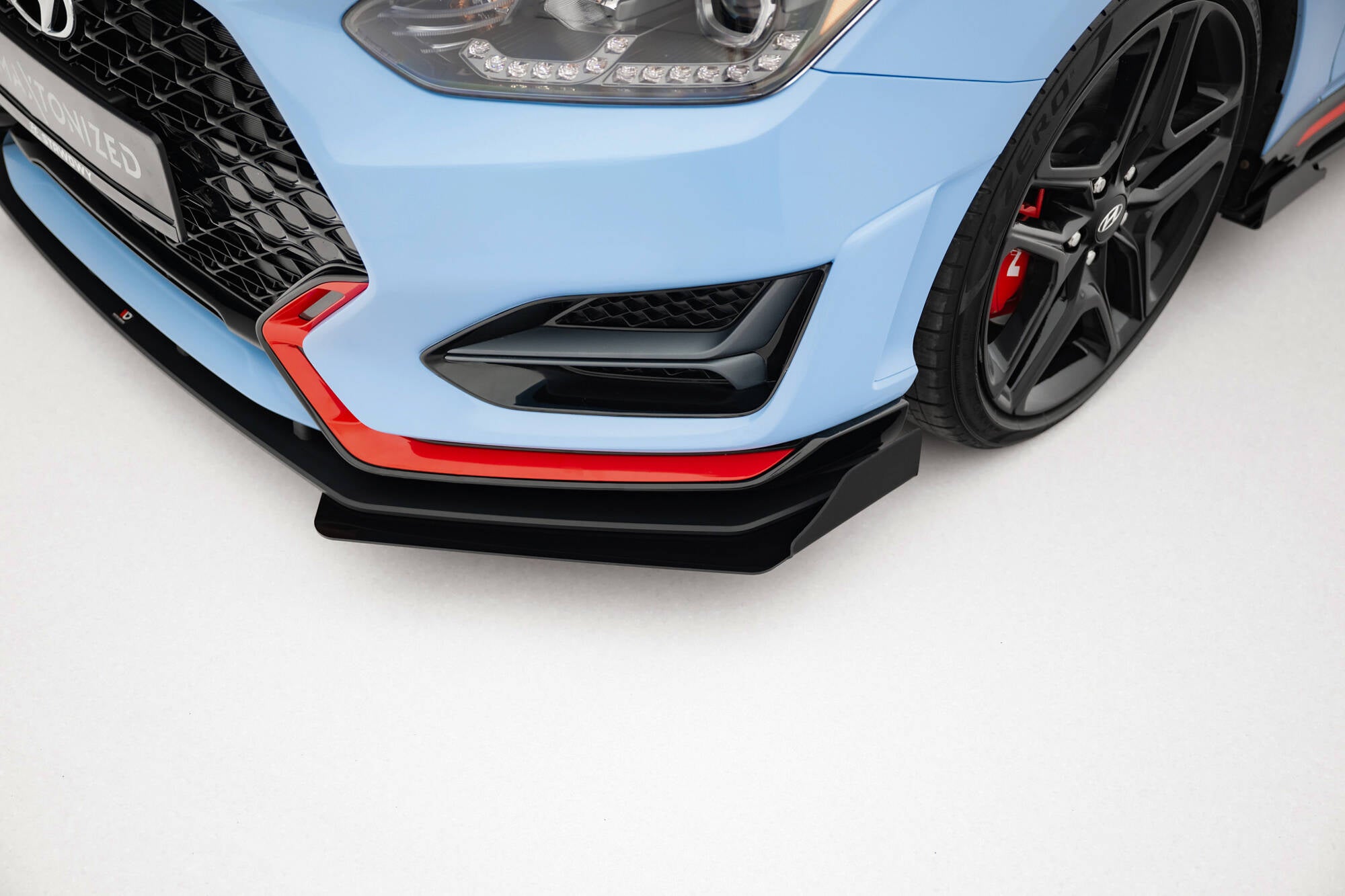 Frontleppe Hyundai Veloster N MK2 med flaps, vist på lyseblå bil med svarte felger og røde bremsekalipere.