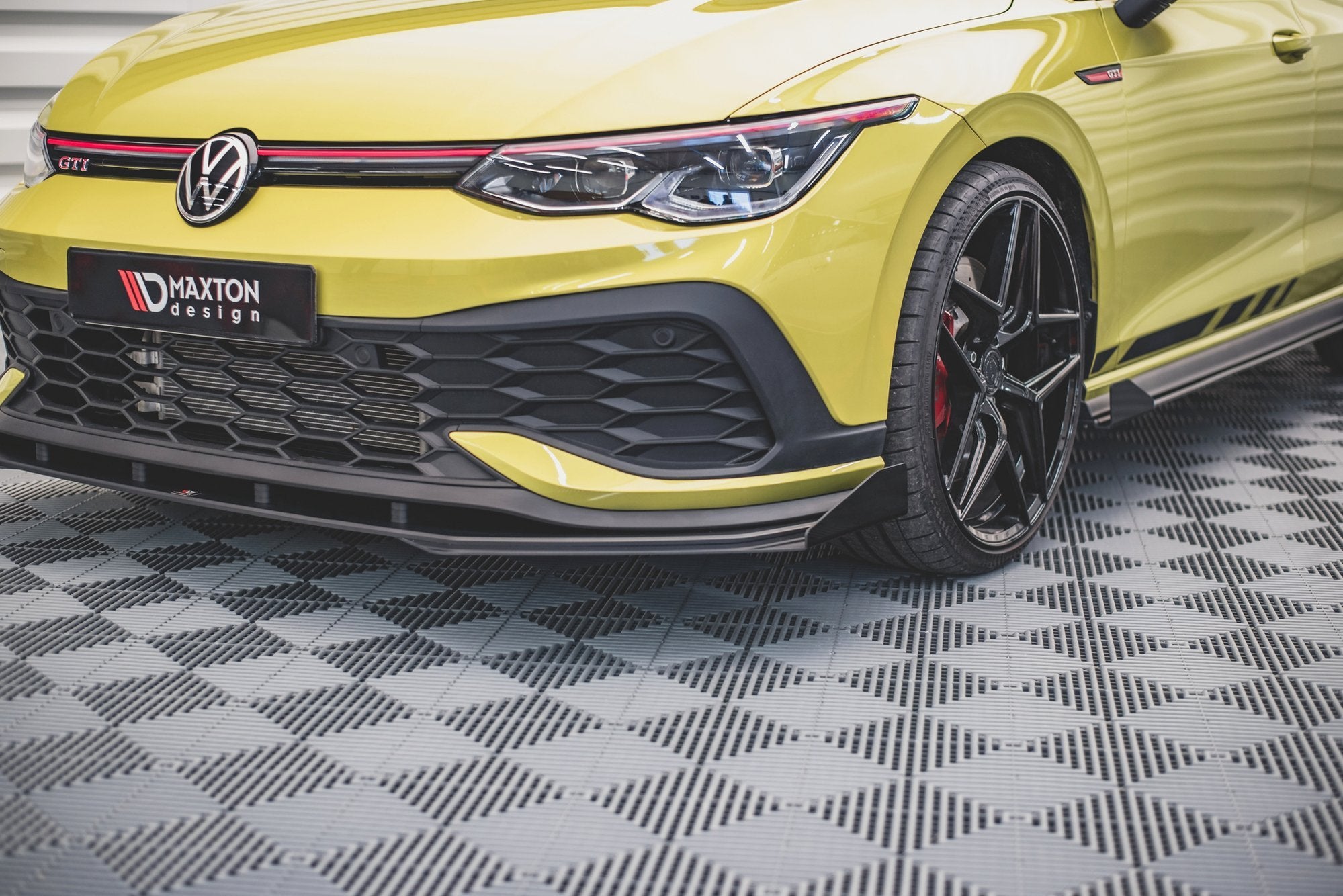Spoiler VW Golf GTI Clubsport MK8 med flaps, nærbilde av høyre frontlykt, sort grill og Maxton-logo.