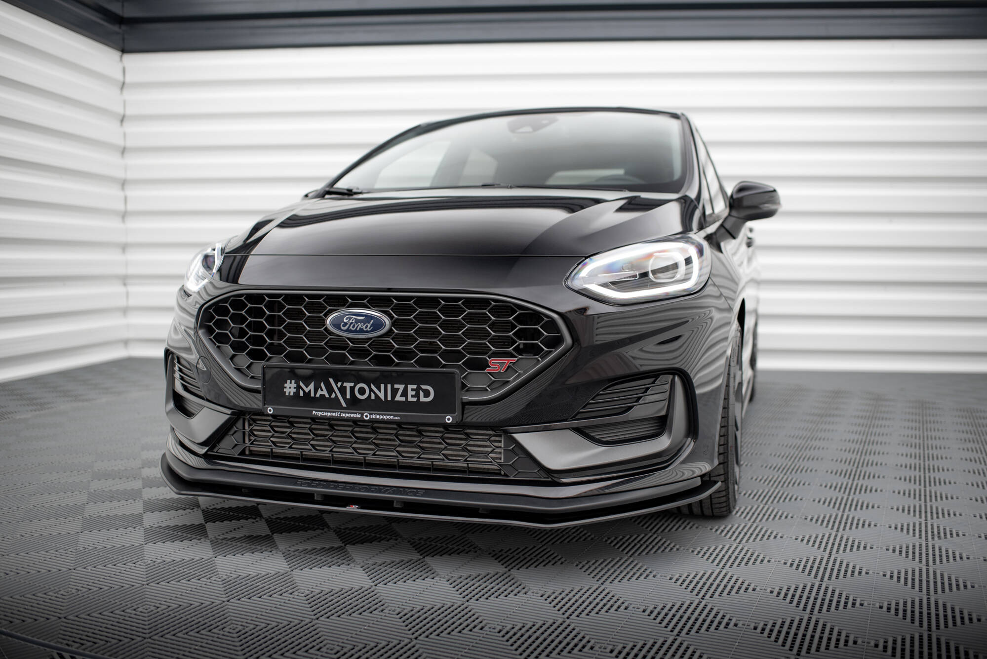 Frontspoiler Ford Fiesta St MK8 Facelift 2021 vist forfra med sekskantet grill og LED-lys på sort bil.