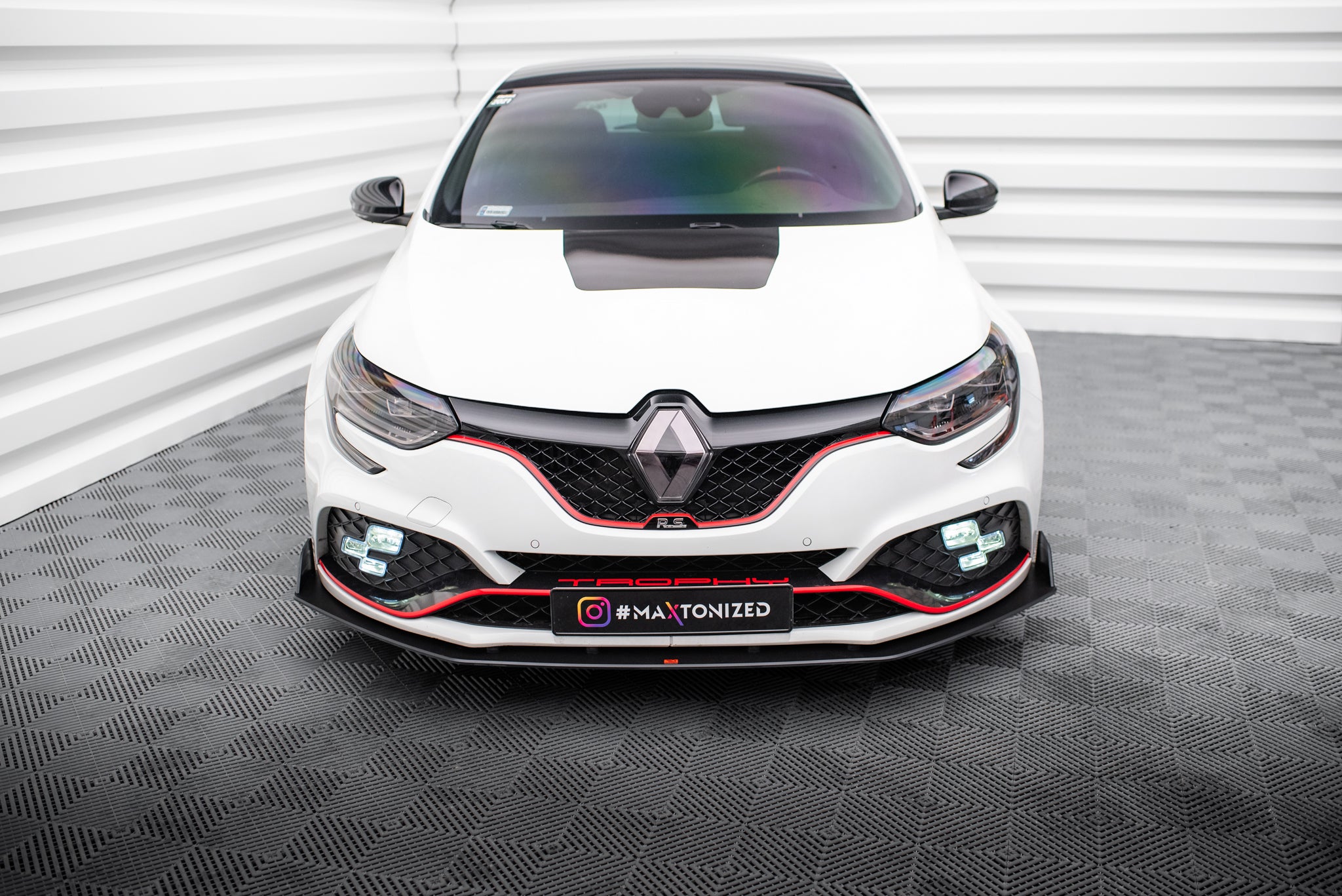 Frontleppe på Renault Megane RS MK4 med rød stripe, sorte detaljer og synlige LED-lys, frontvisning.