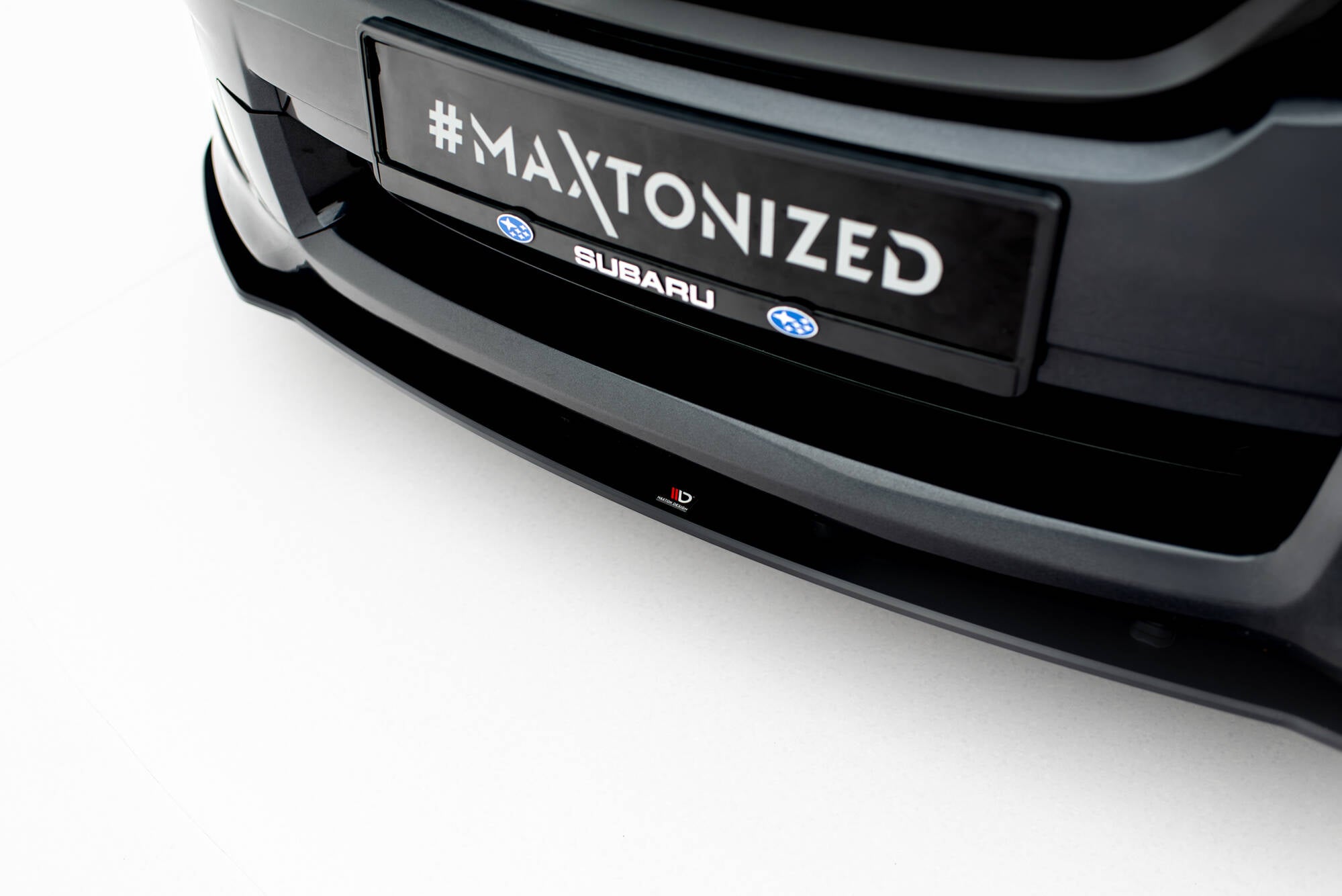 Spoiler til Subaru Impreza WRX Sti MK3 Facelift, sort blank frontsplitter med logo, sett skrått forfra.