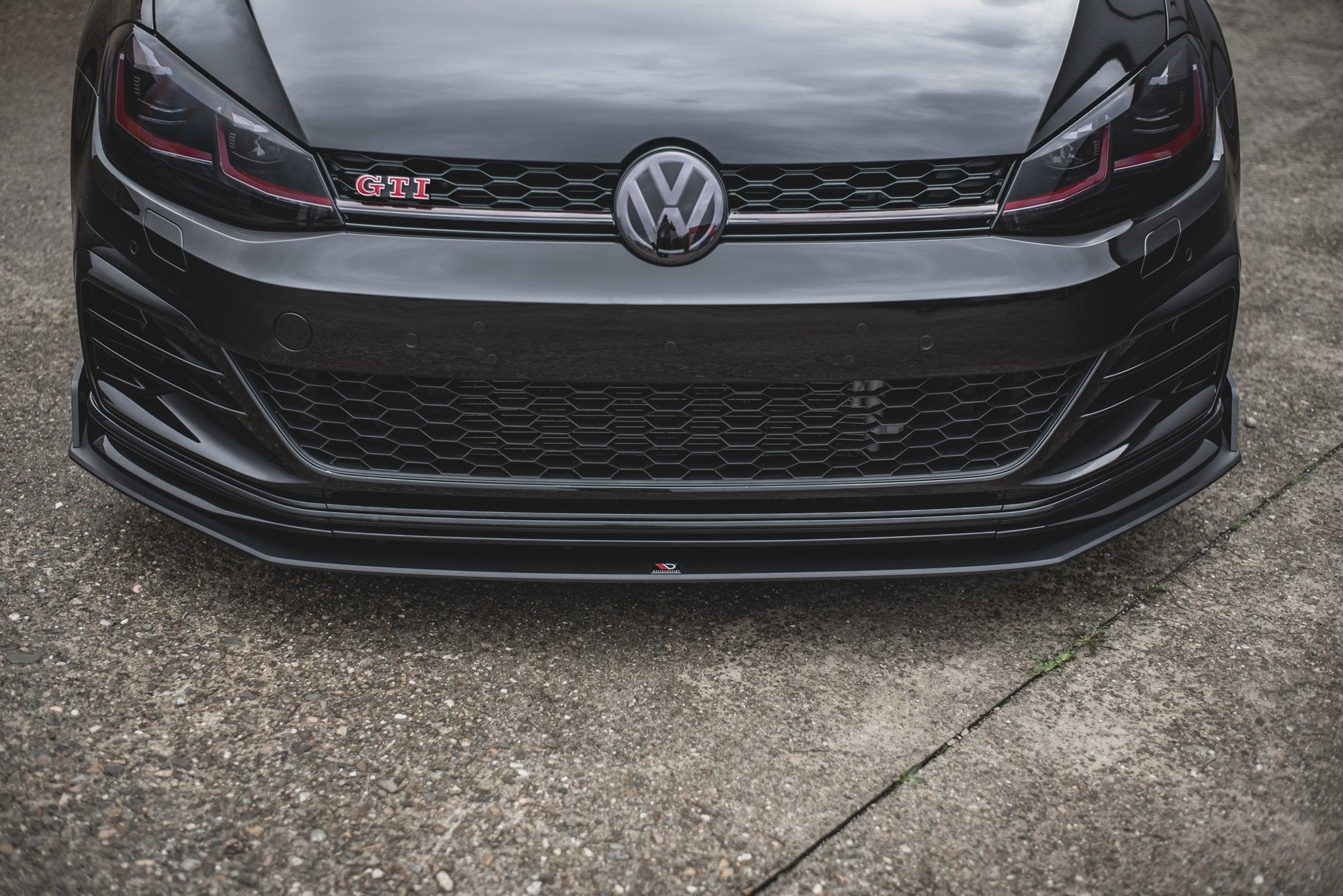 Frontspoiler VW Golf 7 GTI Tcr med sort blank finish, røde detaljer og GTI-logo sett rett forfra.