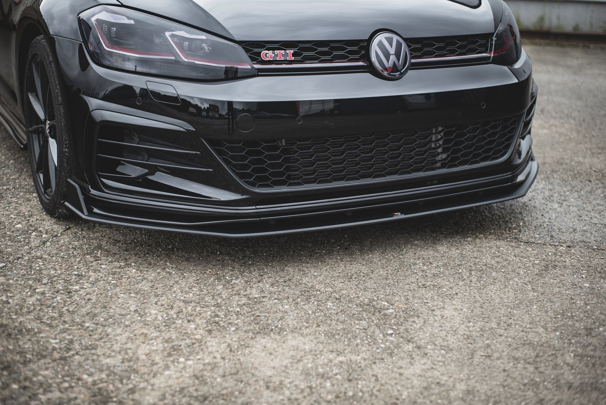 Front splitter på VW Golf 7 GTI Tcr, sort blank plast med rød dekorstripe montert under støtfanger.