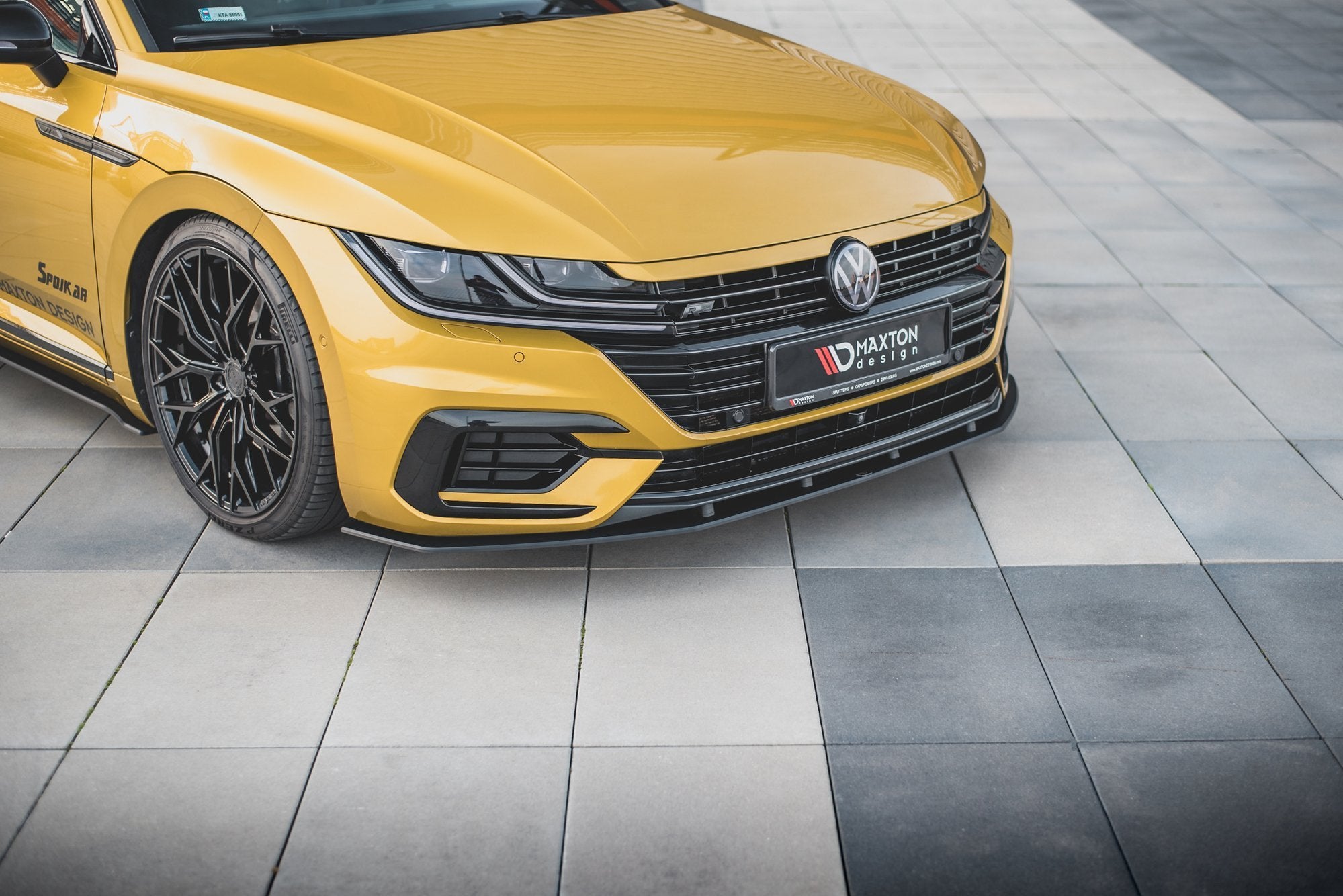 Frontleppe på VW Arteon R-Line med gullfarge, sorte felger og markant grill sett skrått forfra.