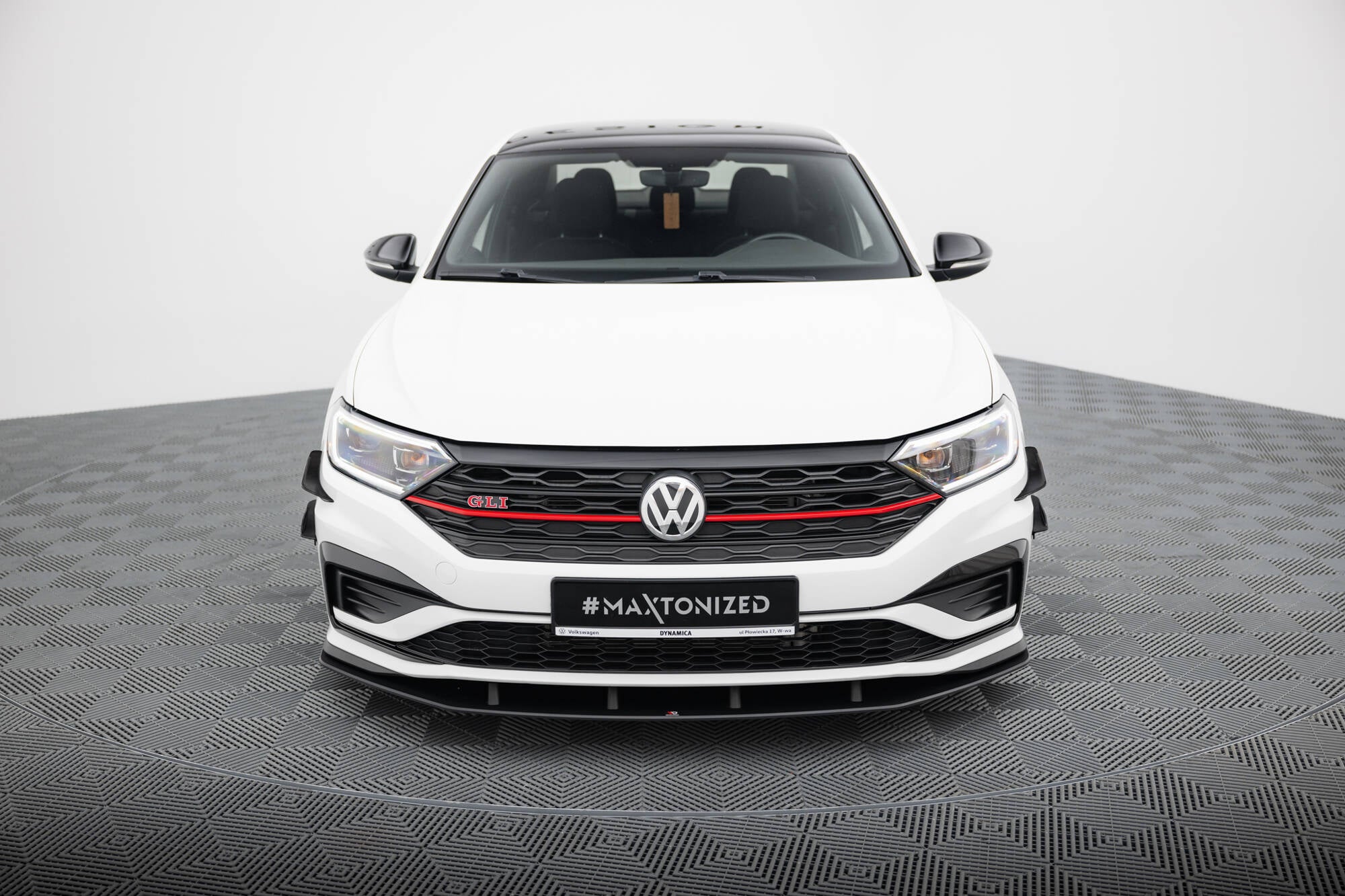 Frontleppe på VW Jetta Gli MK7 med sort grill, røde detaljer og svarte sidespeil, sett forfra.