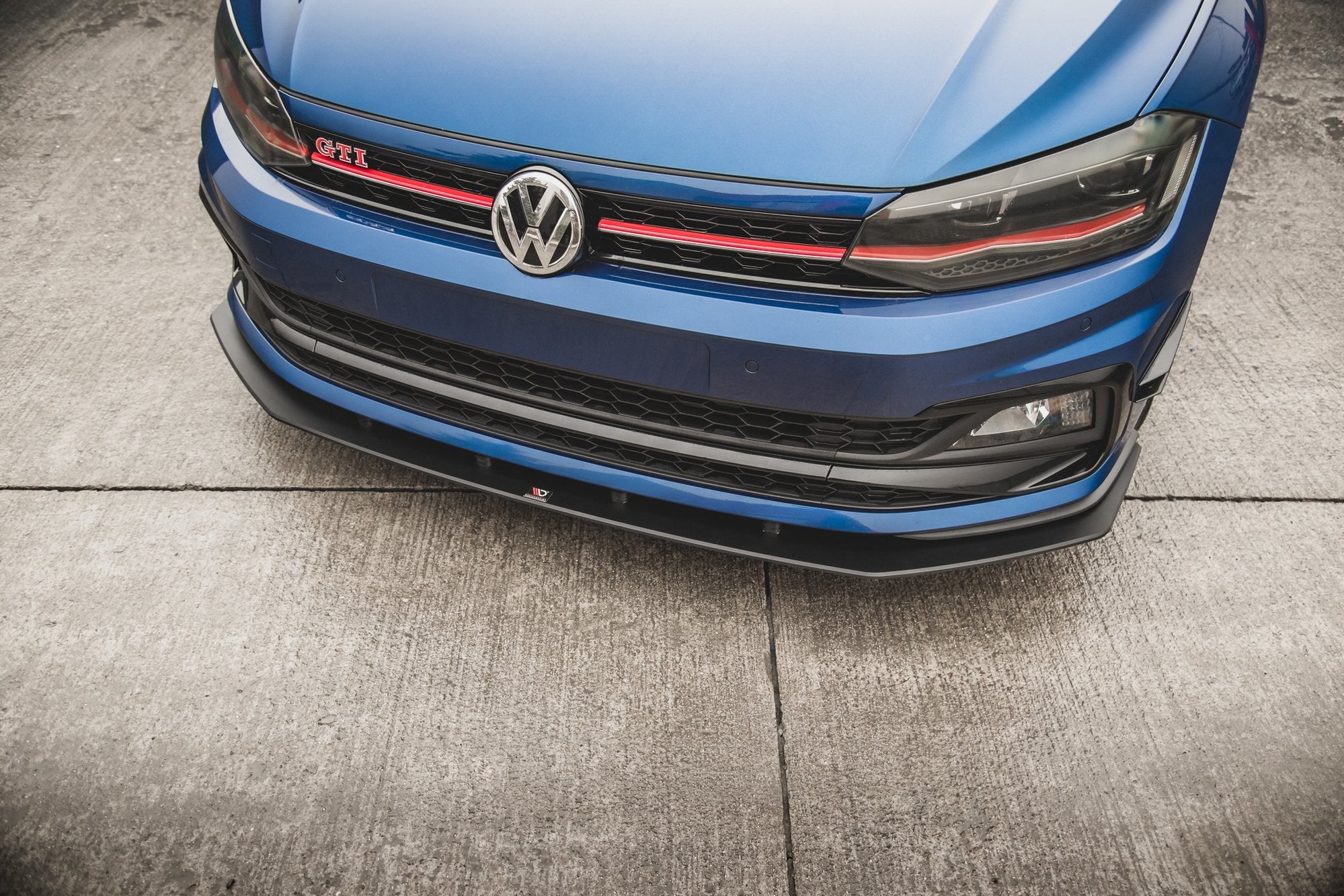 Front splitter på VW Polo GTI MK6, blå bil med sorte detaljer og rød grill sett forfra i skrå vinkel.