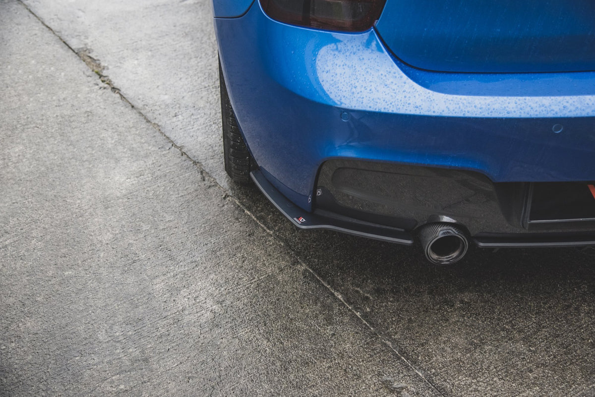 Sideflaps bak i sort finish montert på BMW M135i F20, sett fra skrå vinkel bakfra