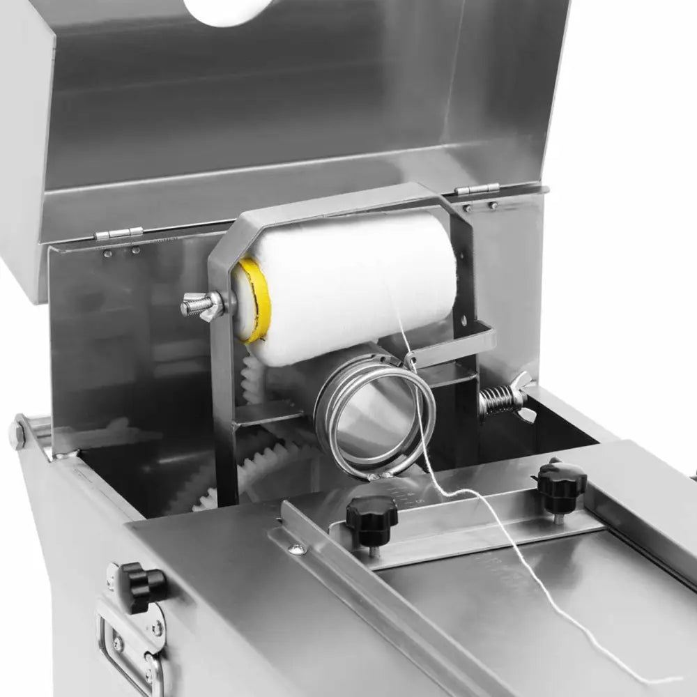 Pølsebinding maskin, nærbilde av innsiden med hvit trådrull og synlige tannhjul i rustfritt stål.