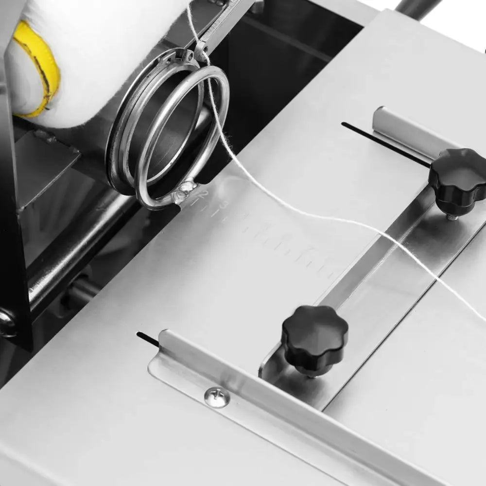 Pølsebinding maskin håndholdt, nærbilde av metallkomponenter med sorte skruer og hvit tråd i ringer.