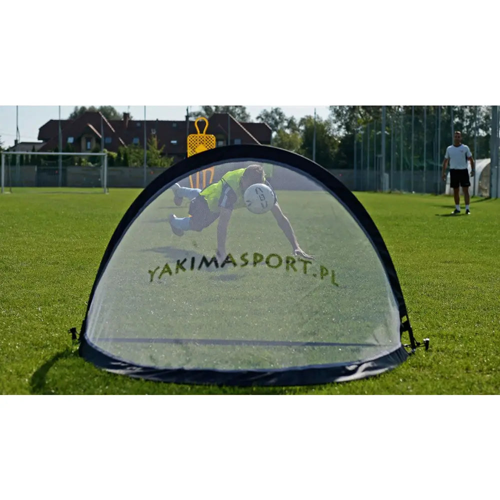 Pop-up portabelt fotballmål 120x80 cm sett forfra på gress, med synlig logo og spiller i bakgrunnen.