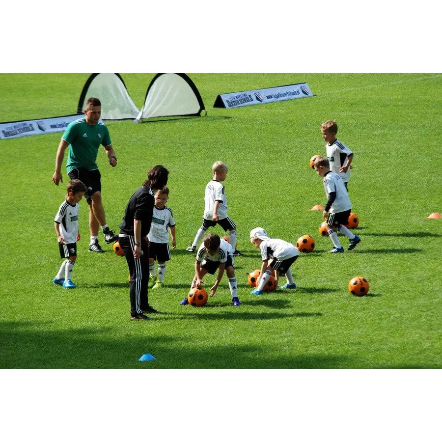 Pop-up portabel fotballport 120x80 cm i bruk under barnefotballtrening på gress med instruktører.