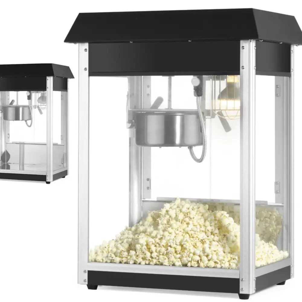 Popcornpoppemaskin med svart topp og sølvrammer, sett fra skrå vinkel med ferskt popcorn inni.