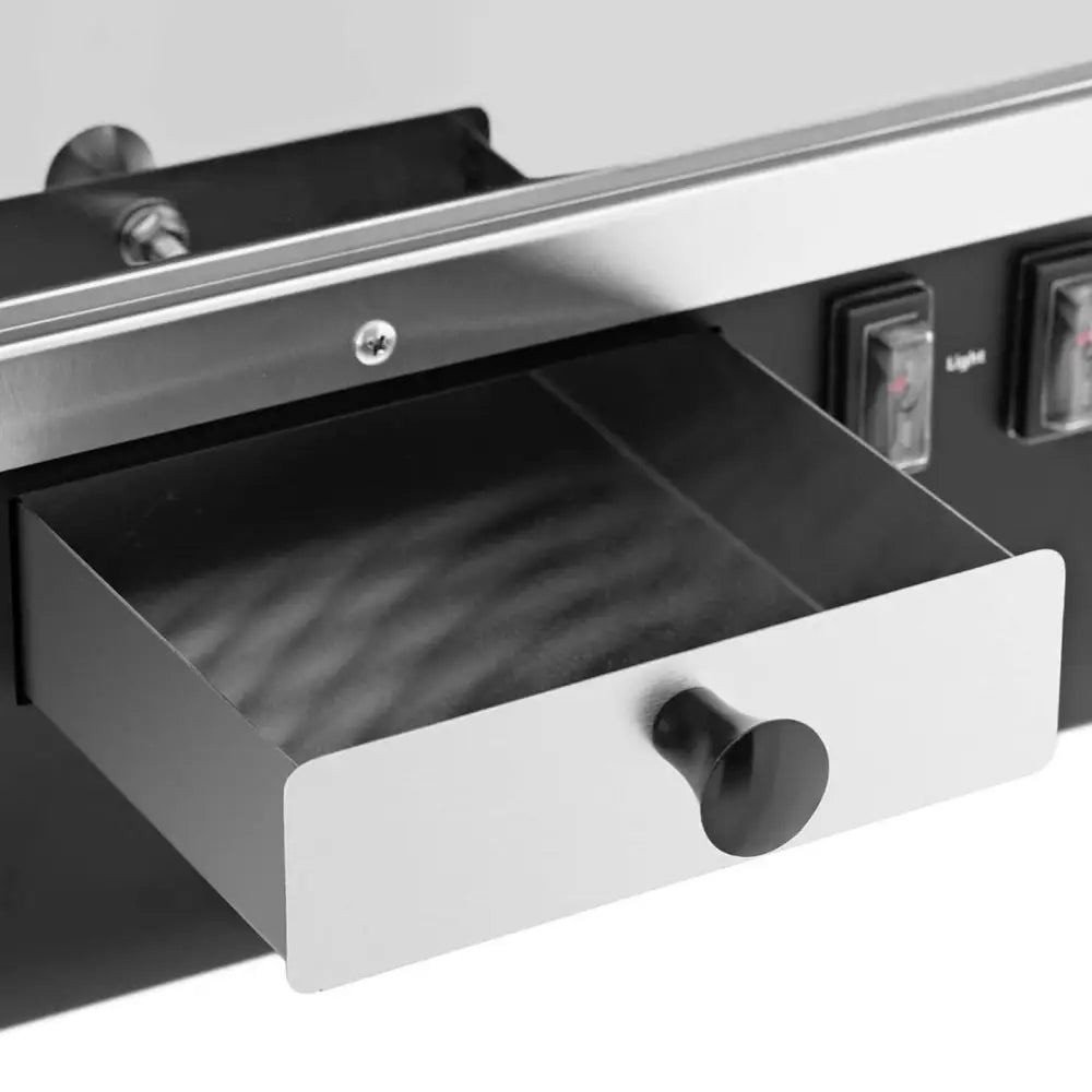 Poppemaskin, detalj av uttrekkbar metallskuff med svart håndtak og børstet ståloverflate.