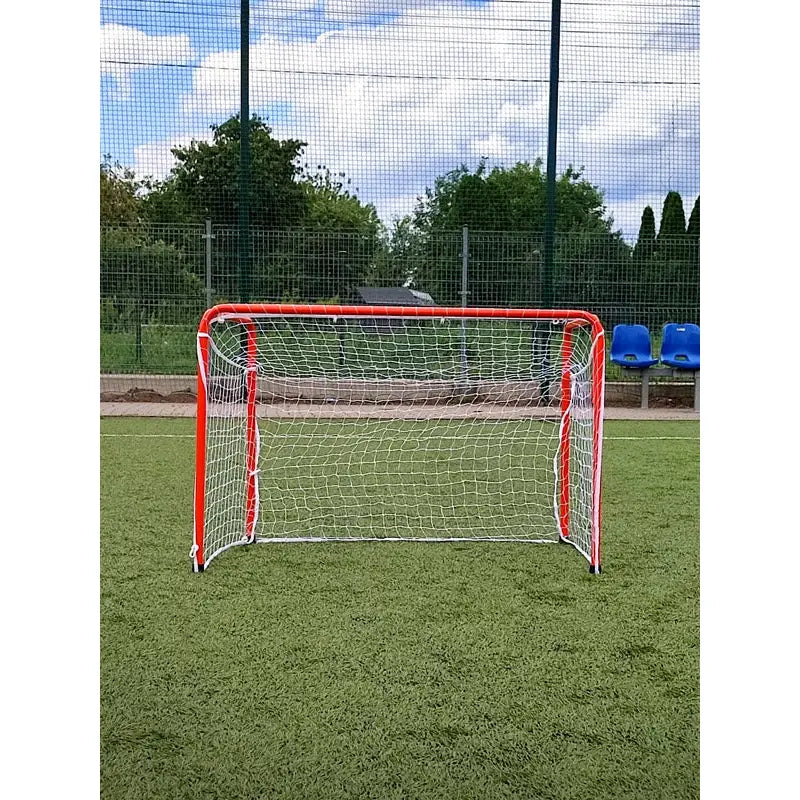 Fotballmål Port Economy med rød ramme og hvitt nett, frontvisning på kunstgressbane med blå seter bak.