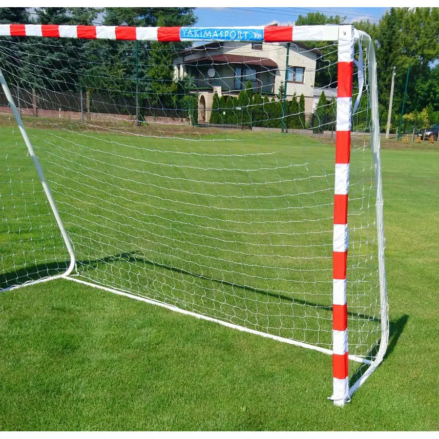 Fotballmål Port Mars med røde og hvite striper, sett fra siden på gressbane med nett montert.