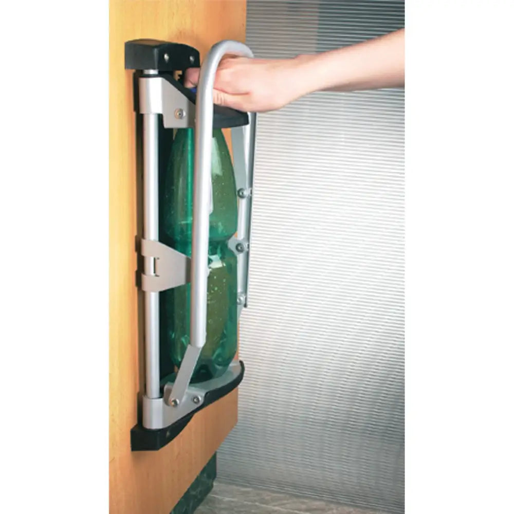 Pressmaskin EcoPress veggmontert, hånd presser grønn PET-flaske ned i metall- og plastmaskin under bruk.