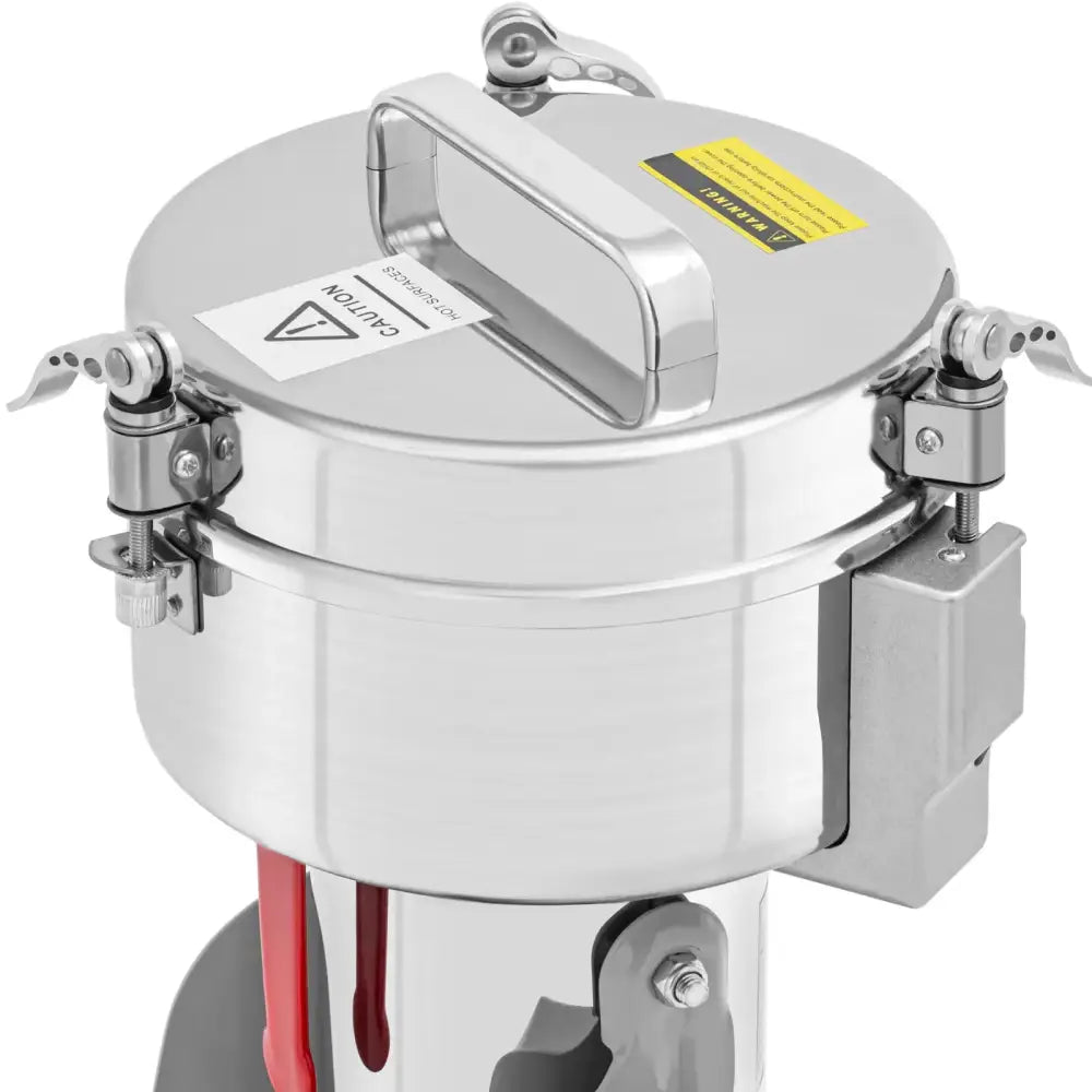 Elektrisk krydderurte- og kaffekvern, skråvisning med bærehåndtak, låsemekanismer og varselsymboler på lokket.