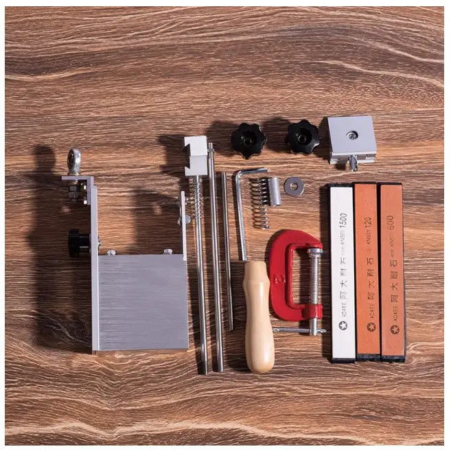 Knivslipesystem med treskaft, to brynesteiner i ulike farger og rød C-klemme, sett ovenfra på tregulv.