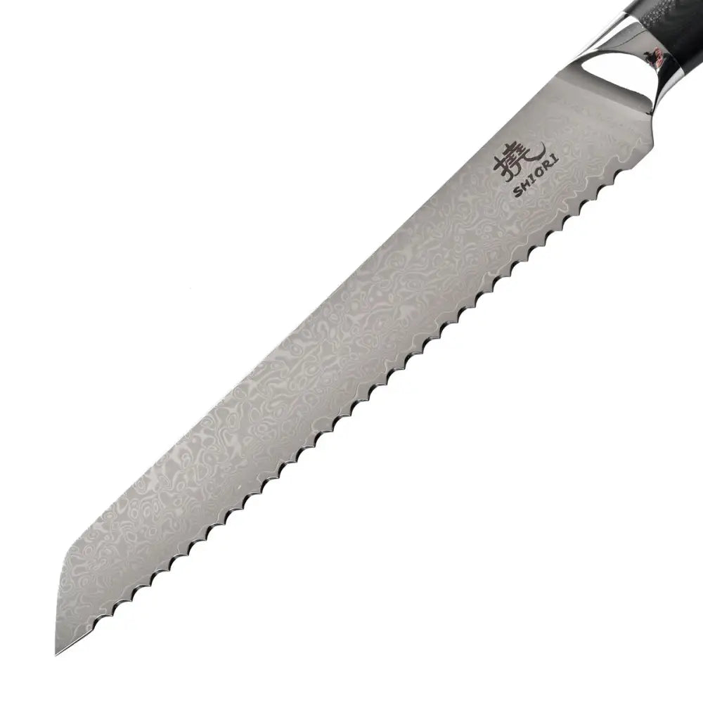 Shiori brødkniv i damaskusstål, nærbilde av tagget blad med dekorativt mønster mot hvit bakgrunn.