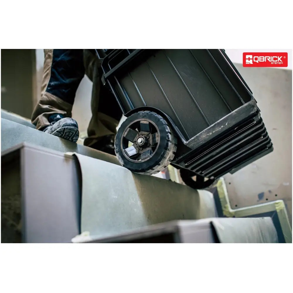 Qbrick System One Cart Techniker, sidebilde som viser robust hjul i bruk ved transport opp trapp.