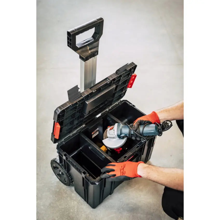 Qbrick verktøykasse sett Two 6I1, åpen visning med vinkelsliper plassert i romslig inndeling av person med oransje hansker.