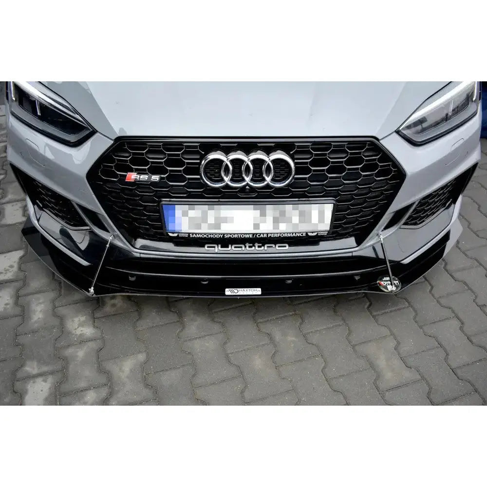 Front splitter på Audi Rs5 F5 med sort bikubemønstret grill og metallstag, sett forfra i gateperspektiv.