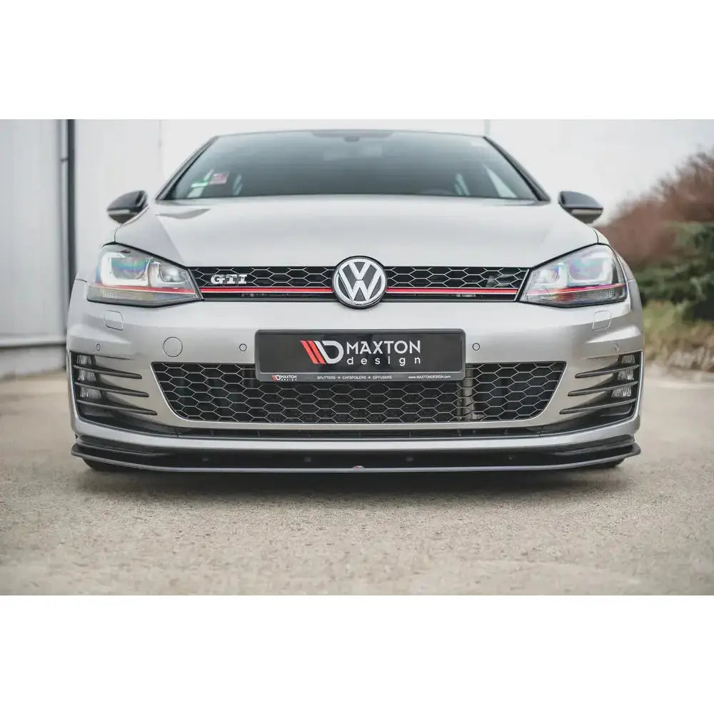 Spoiler på VW Golf 7 GTI sett forfra med sort frontsplitter, røde detaljer og bikubemønstret grill.