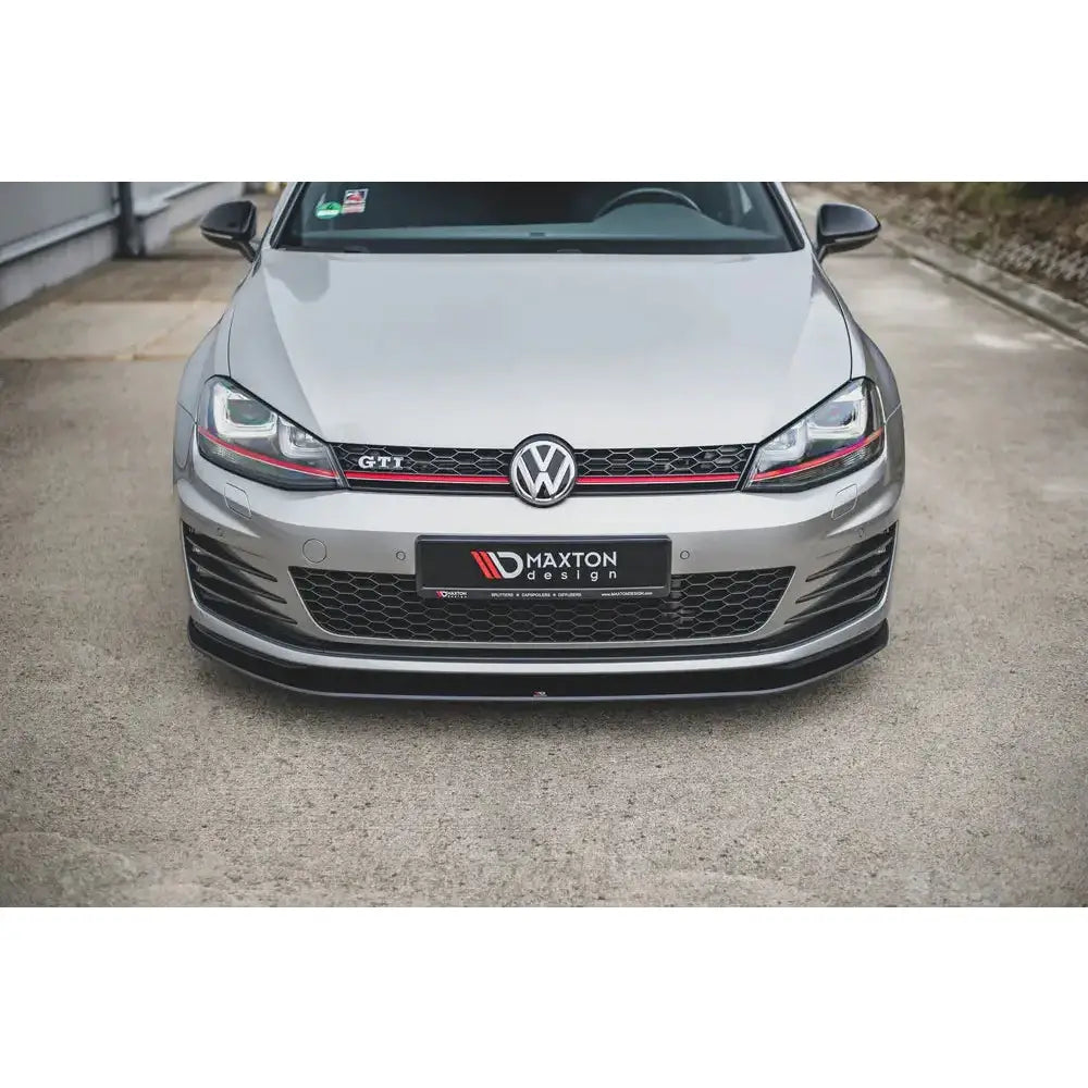 Front splitter på VW Golf 7 GTI, sølvfarget bil med svart frontspoiler og rød grilldetalj.