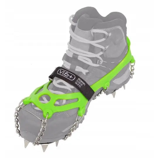 Raczki Pro Traxion, grønn stegjern med metallpigger og svart stropp, festet på sko fra skrå vinkel.