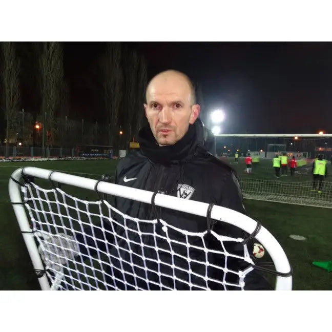 Rebounder MINI for keepertrening, mann tester hvitt og svart nett på kunstgressbane under flomlys.