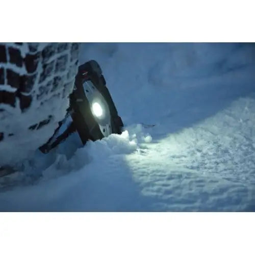 LED-reflektor med høyttaler, montert på hjul med kjettinger som lyser opp snødekket under dekket.