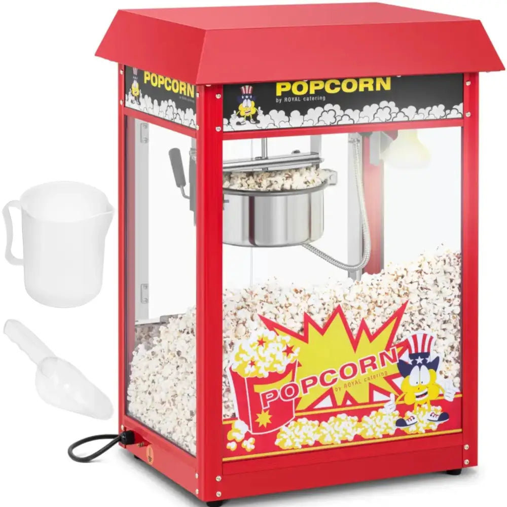 Retro popcornmaskin i rød metall og glass, fylt med popcorn, med dekor, målekopp og plastskje ved siden av.