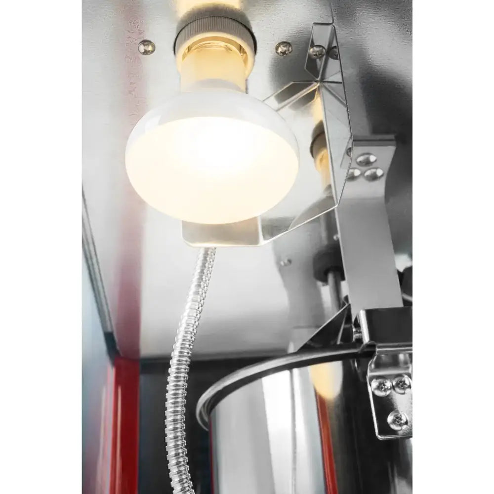 Retro popcornmaskin, nærbilde av lyspære og metallslange i taket med reflekterende ståldetaljer.