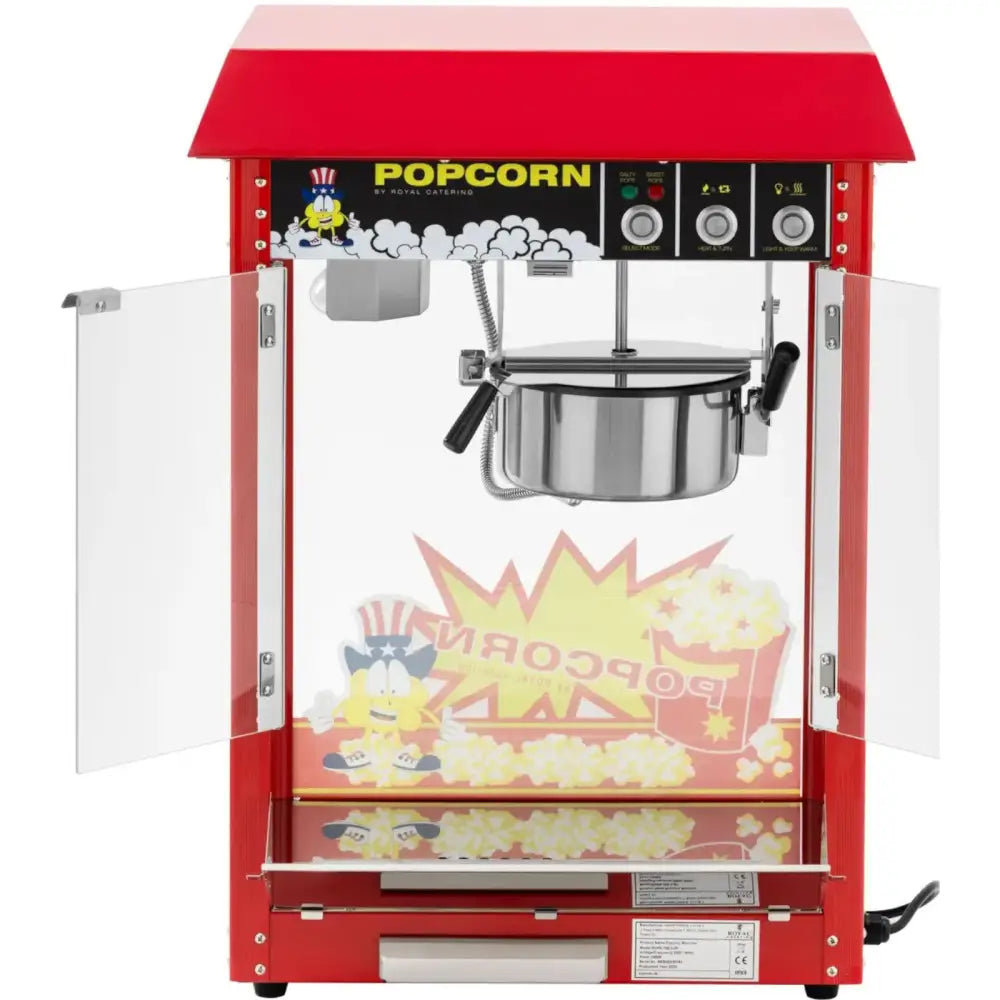 Retro popcornmaskin i rødt metall, åpne glassdører, synlig stålkjele og dekorative popcornmotiver nederst.