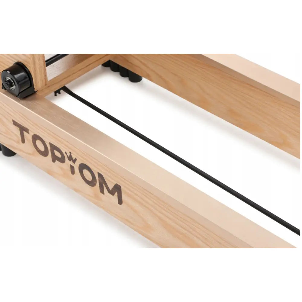 Romaskin i lyst treverk, nærbilde viser markert åremønster, sort logo og synlig wire mot plastdetaljer.