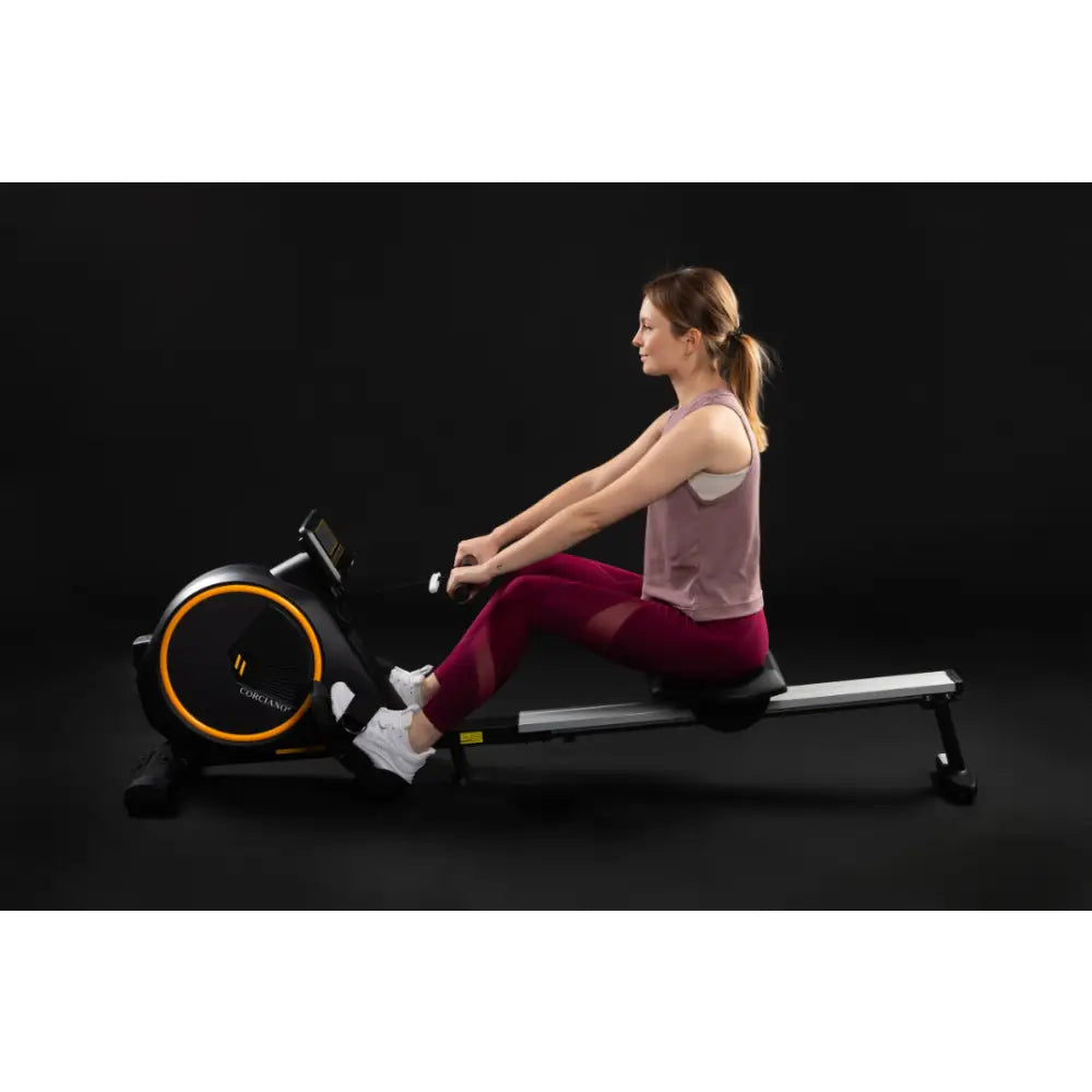Romaskin Omega sammenleggbar, sort og sølv modell i bruk av kvinne, sidevisning, oransje detaljer og digital skjerm.