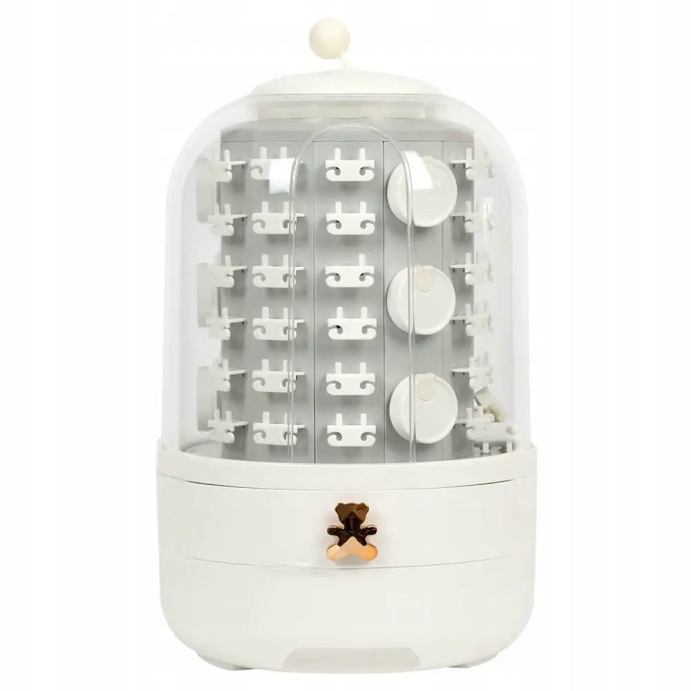 Roterende smykkeorganisator i hvit plast, sylinderform med gjennomsiktig lokk, kroker og skuffer synlig.