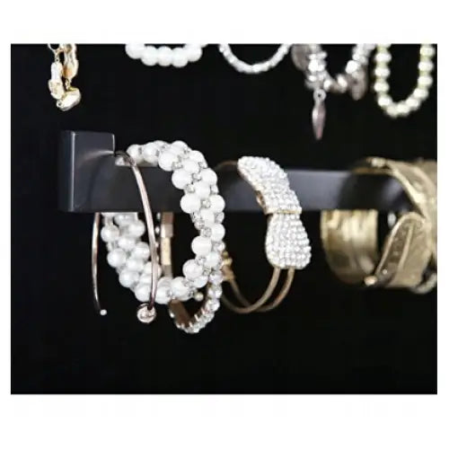 Roterende smykkeskap, detaljert sidebilde av sort metallstang med hengende armbånd og pannebånd med perler.