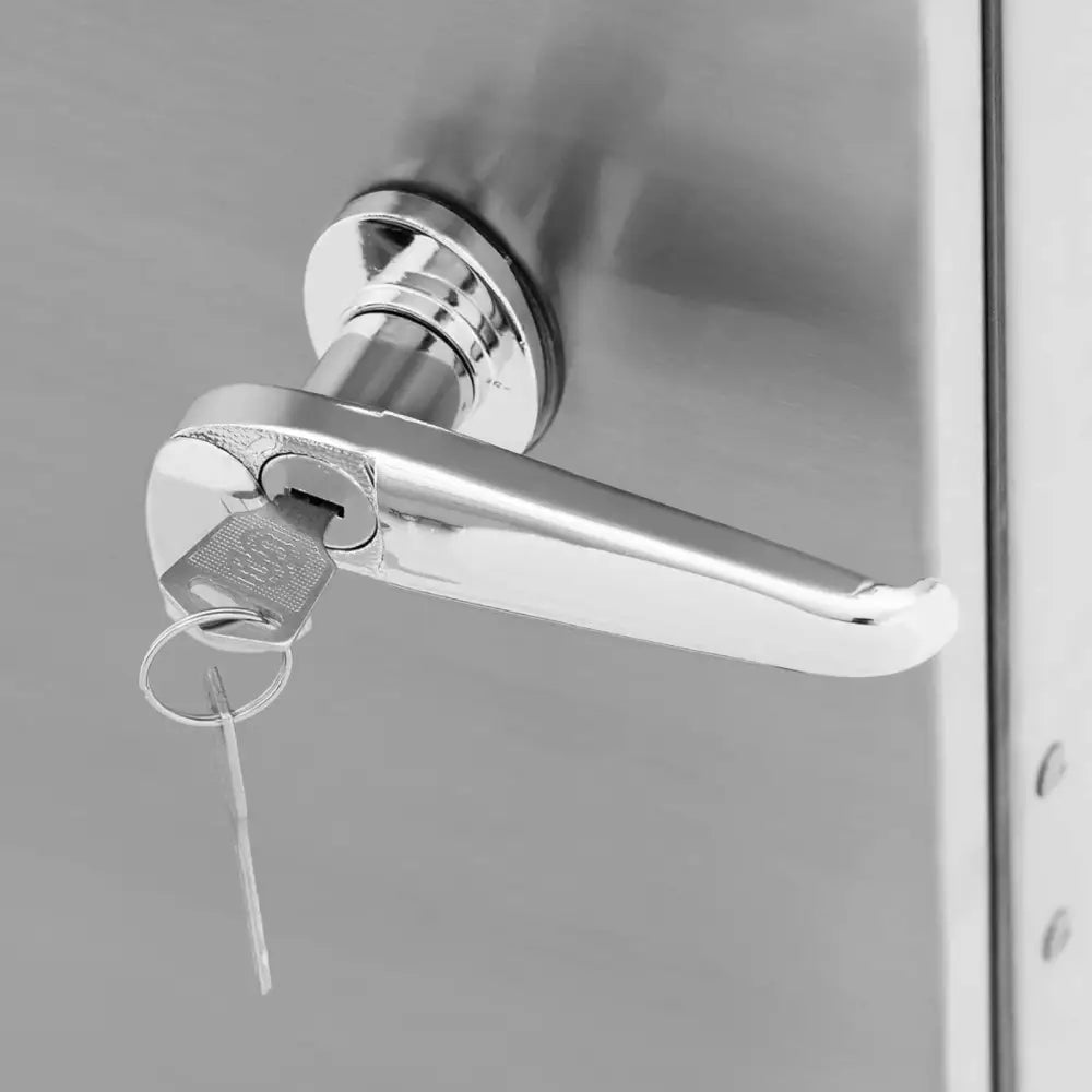 Røykovn metallhåndtak sett fra siden, nøkkel i låsen og reflekterende sølvfinish på døren.