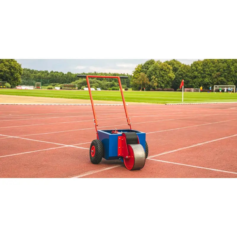 Rulleskate for linjemaling, blå og rød maskin med store gummihjul og rødt håndtak på friidrettsbane.
