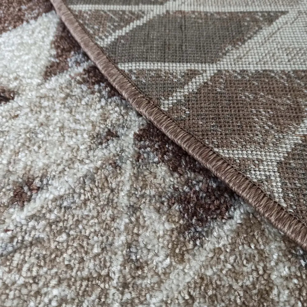 Rundt brunt teppe Panama, nærbilde av geometrisk mønster og markert beige kantbånd.